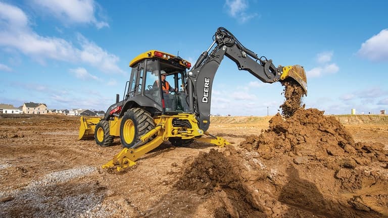 An operator dumping dirt from the boom of a 320P backhoe. | 4re Equipment