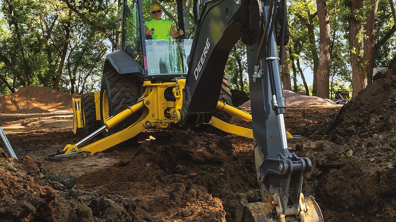An operator using a 710P-Tier Backhoe to scoop dirt out of a hole. | 4re Equipment | ID: 710PBH