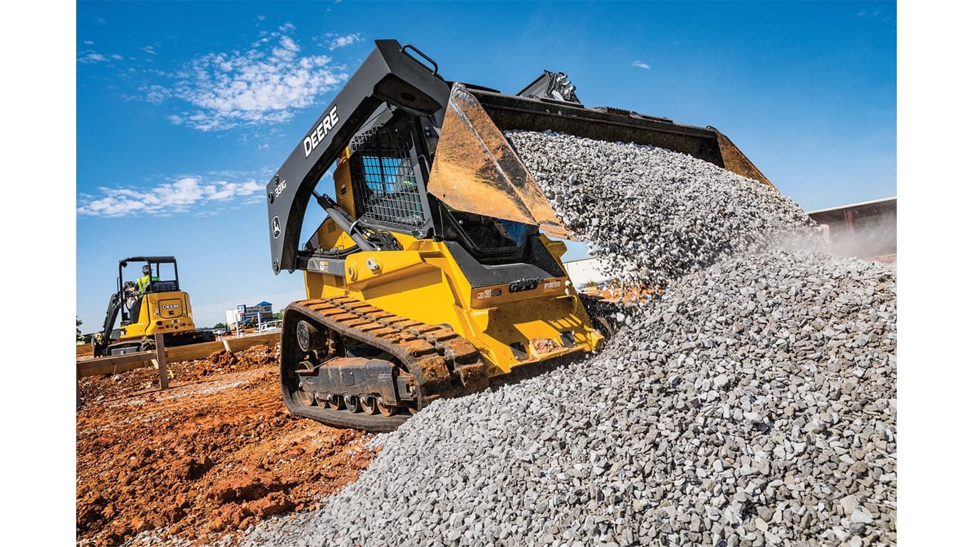 A 331G Compact Track Loader moving rocks at a worksite with a 35G Excavator in the background. | 4re Equipment | ID: 331gxt