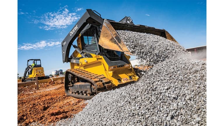 A 331G Compact Track Loader moving rocks at a worksite with a 35G Excavator in the background. | 4re Equipment