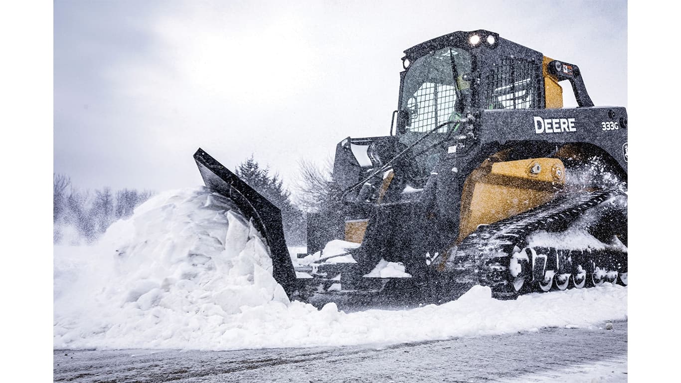 A 333G Compact Track Loader with snow blade attachment plowing snow. | 4re Equipment | ID: 333gxt