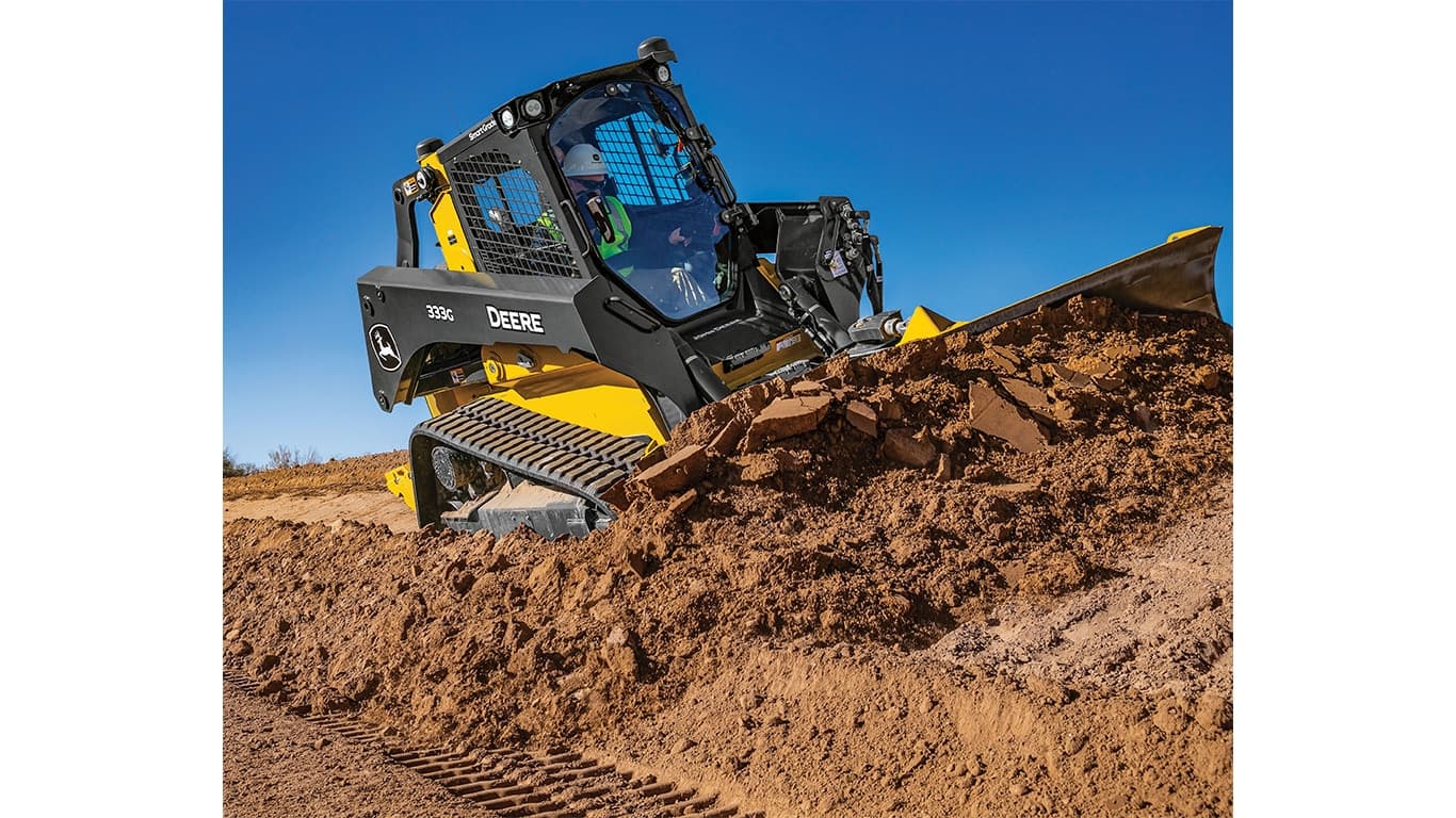 A 333G Compact Track Loader pushes dirt on angled terrain. | 4re Equipment | ID: 333gxt