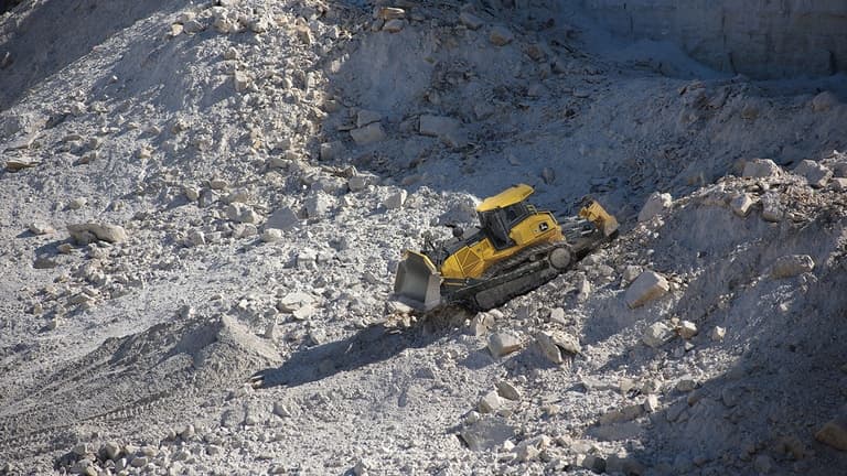 A 1050K Dozer pushing rock at a quarry worksite. | 4re Equipment