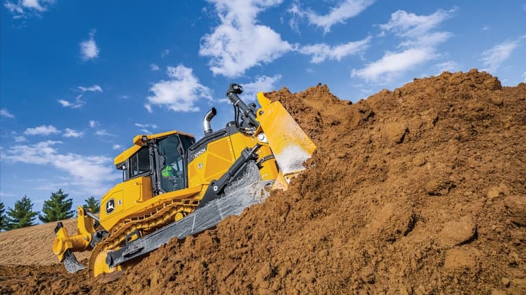 A 1050K Dozer pushing dirt on a hill at a worksite. | 4re Equipment