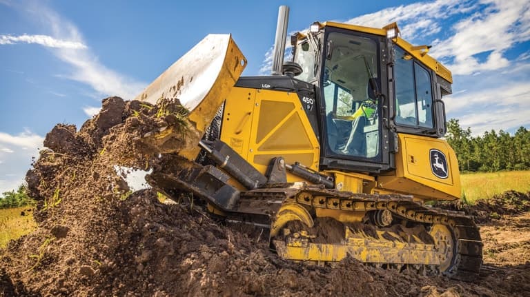 Side view of a 450P Dozer moving dirt. | 4re Equipment