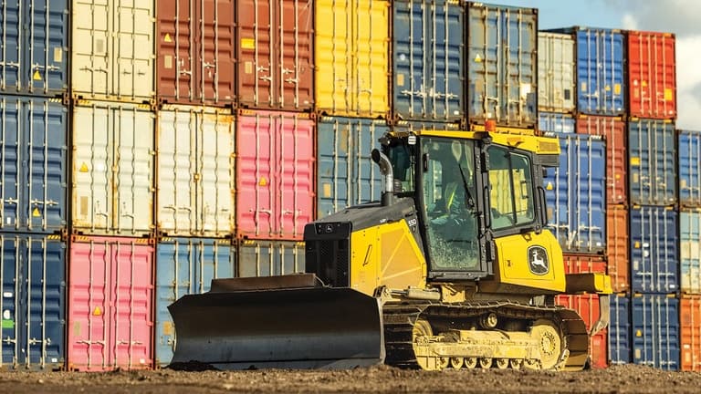 550P Dozer in front of a wall of colorful shipping containers. | 4re Equipment