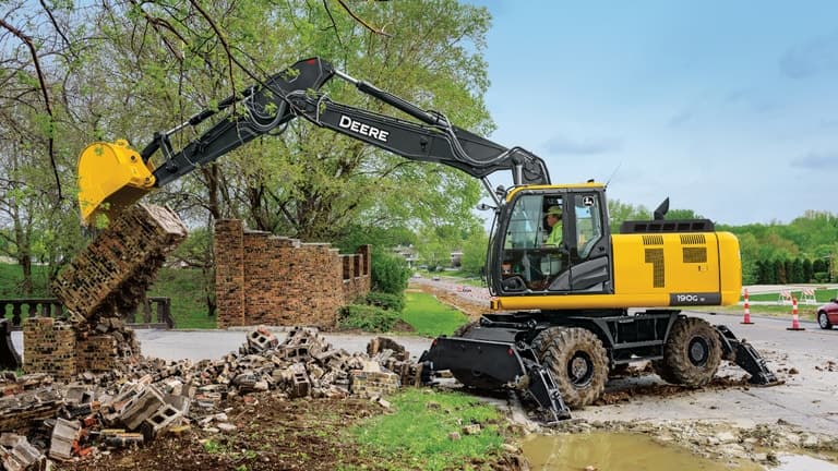 A 190GW Excavator being used to break down a brick wall in front of a road. | 4re Equipment