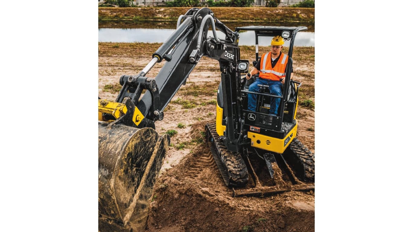 An operator using a 26P-Tier Excavator to scoop dirt at a worksite with a pond in the background. | 4re Equipment | ID: 26PEXFT4