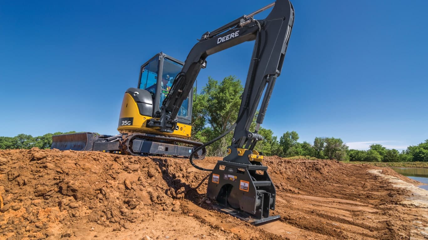 A 35G Excavator with a PC7 plate compactor attachment compacting dirt on a worksite. | 4re Equipment | ID: 035gxff