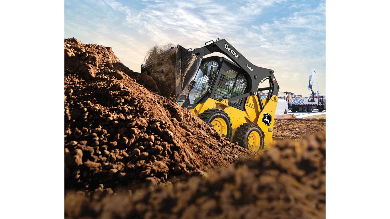 A 318G Skid Steer moves rock and dirt on unleveled terrain. | 4re Equipment | ID: 318gft4
